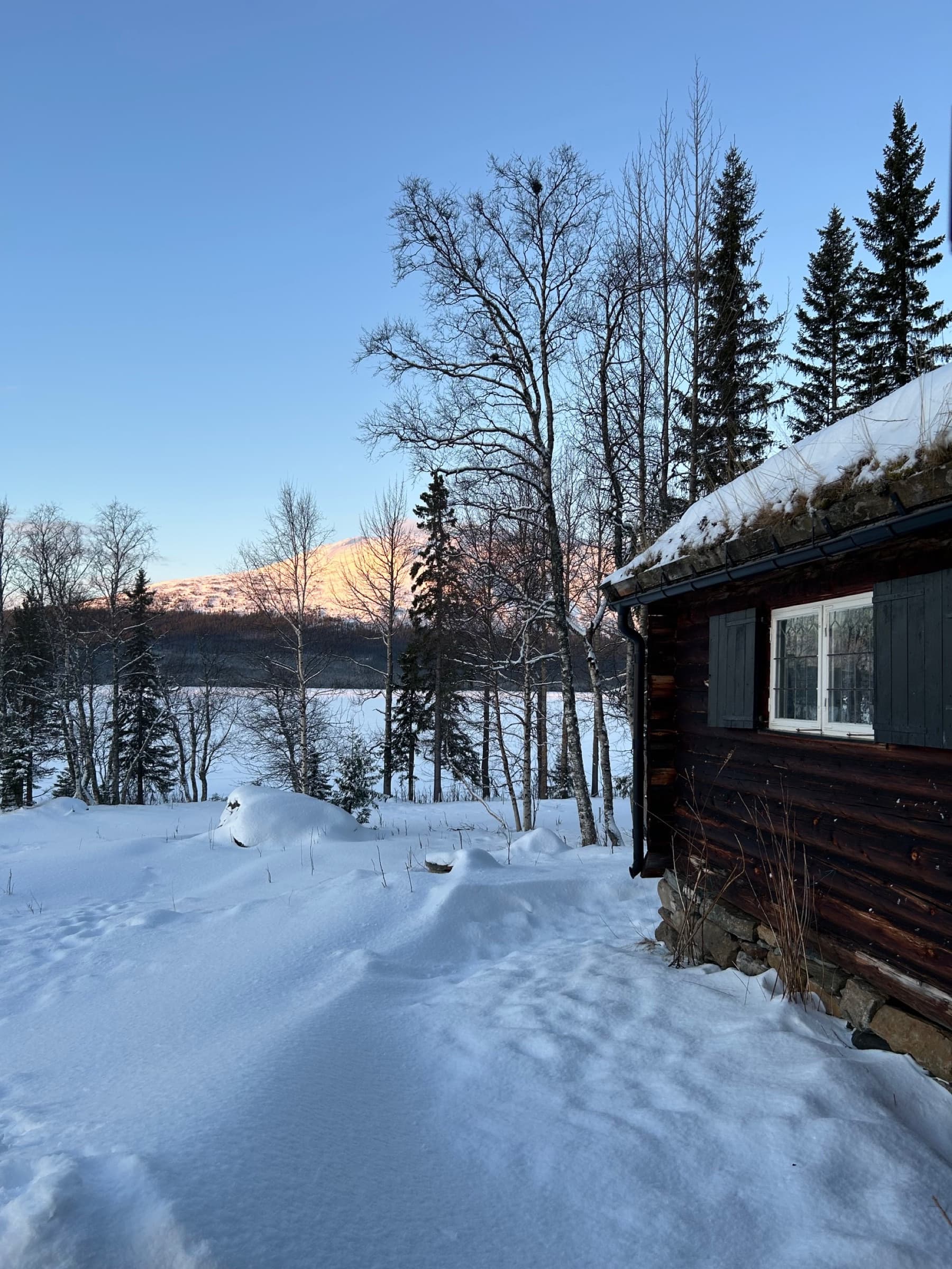 Kvällssol på fjället bortom den frusna sjön